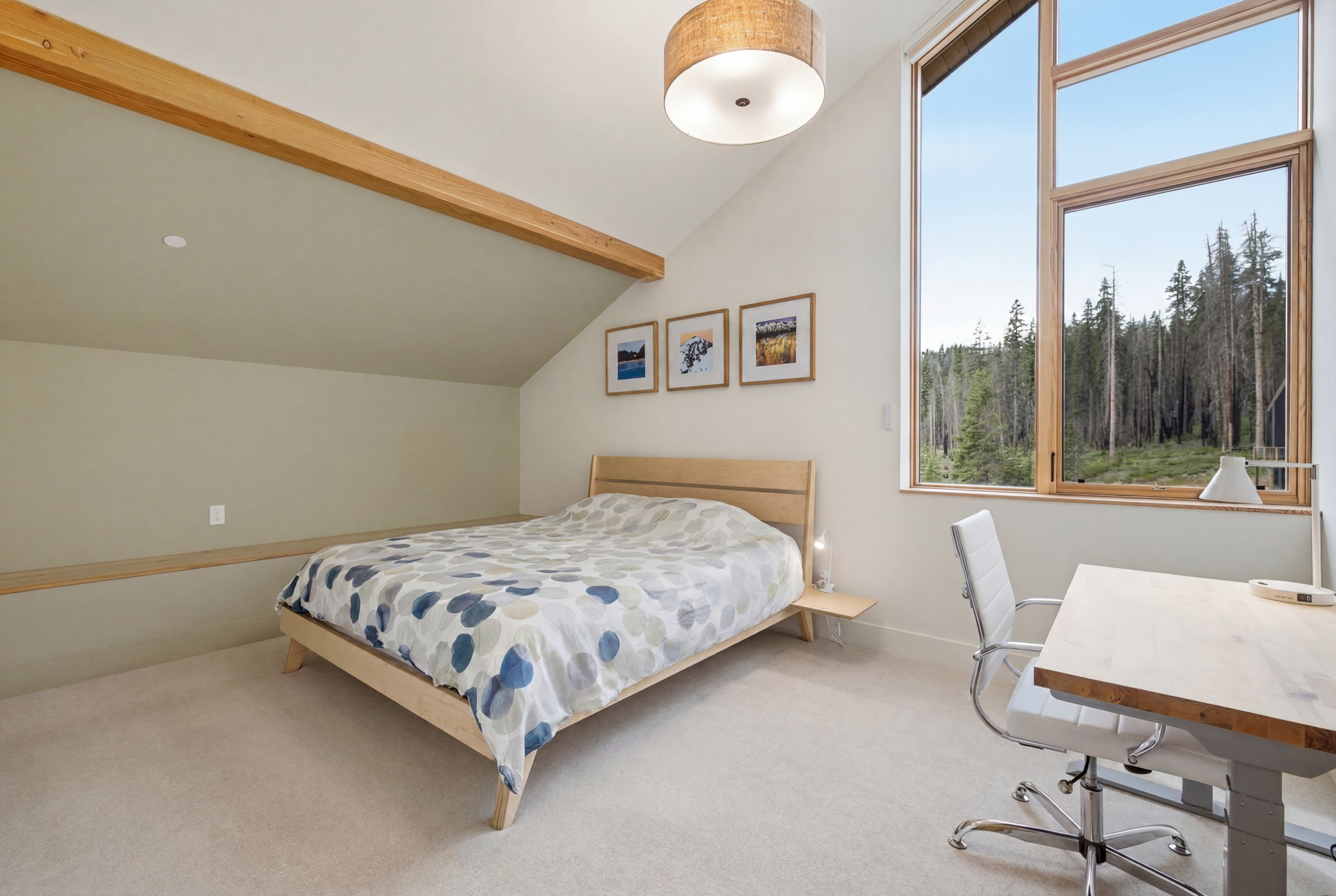Guest bedroom with king bed and work desk with forest view