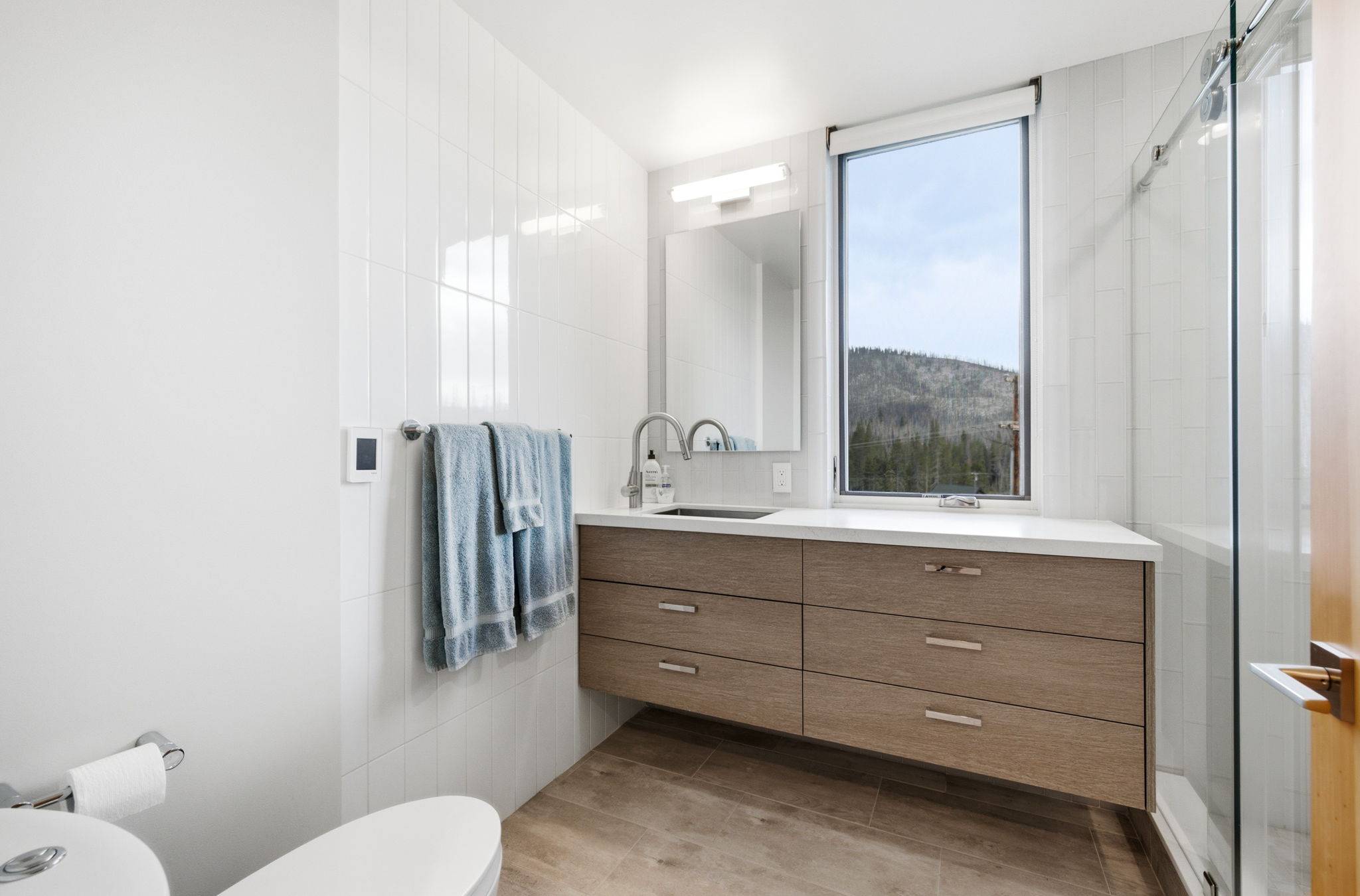 Downstairs bathroom with floating vanity and glass walk-in shower