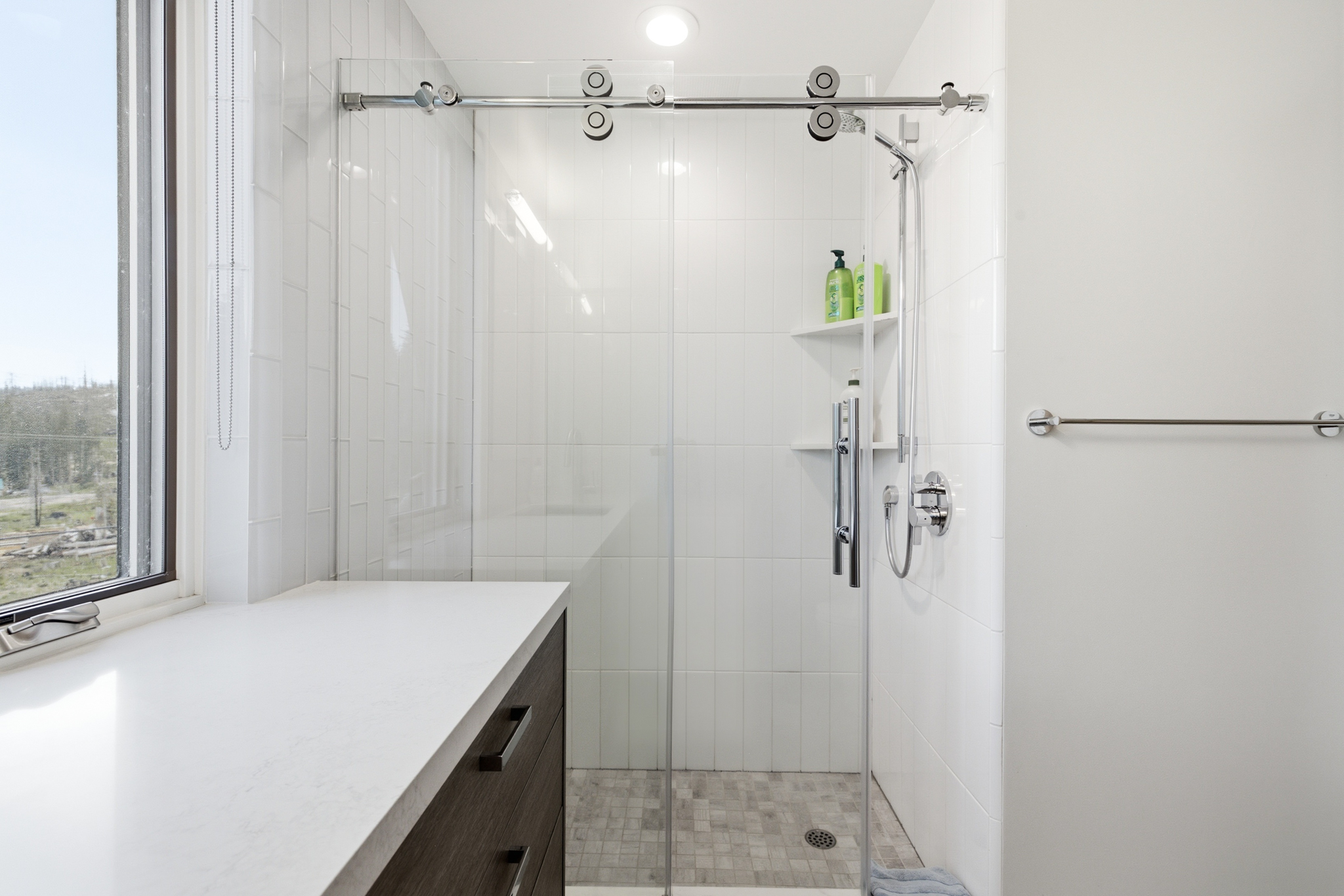 Walk-in shower with glass sliding door and white tile