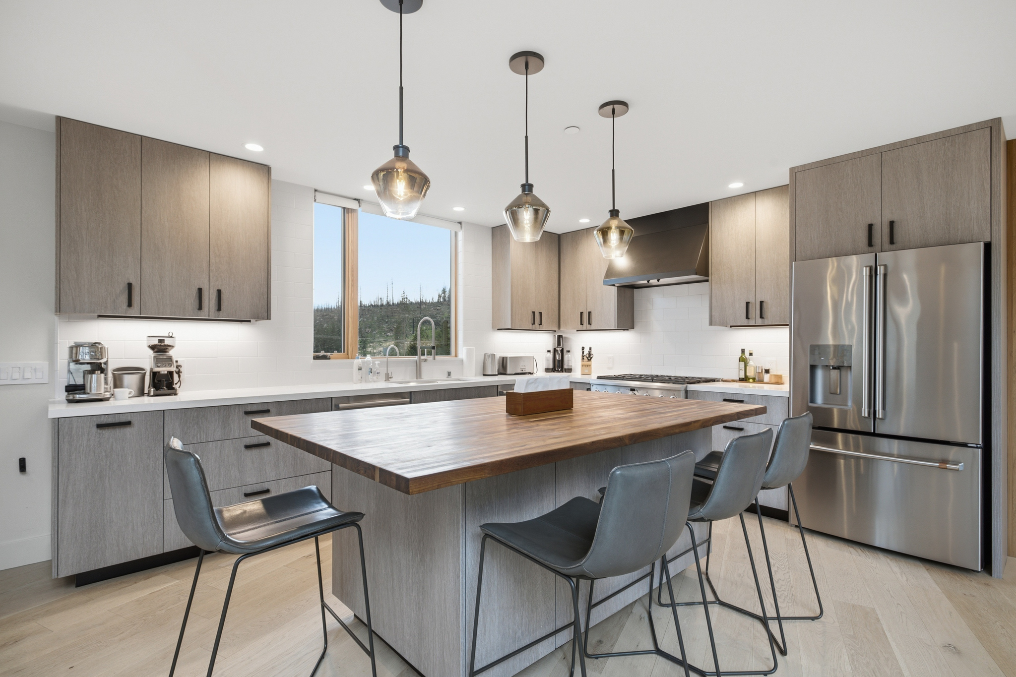 Kitchen with large butcher block island, pendant lights, and bar seating