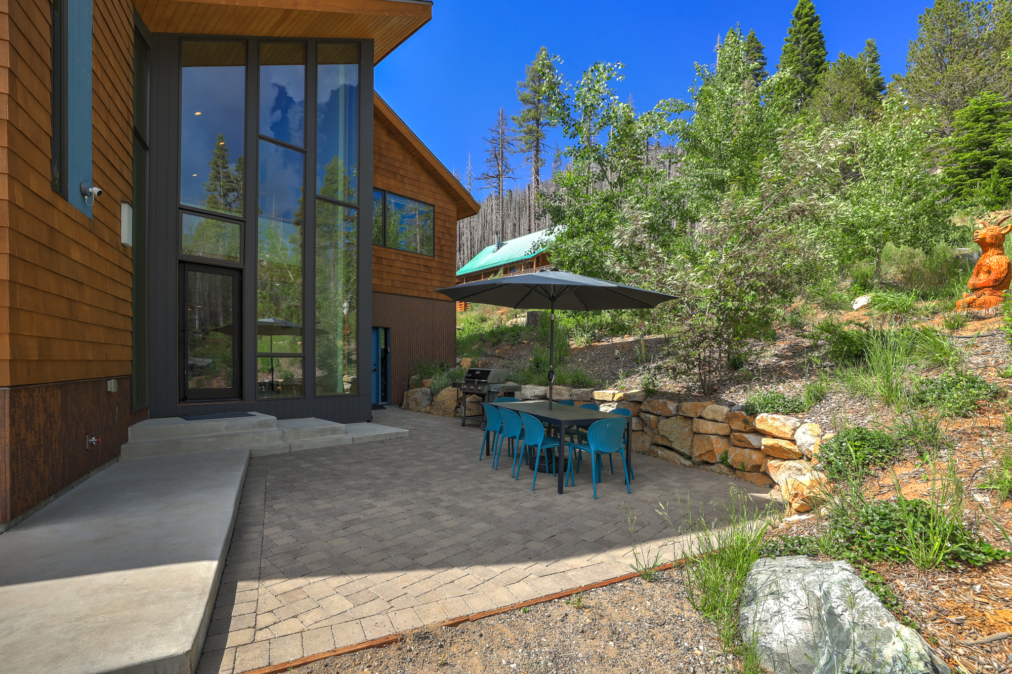 Outdoor patio with dining table, teal chairs, and umbrella