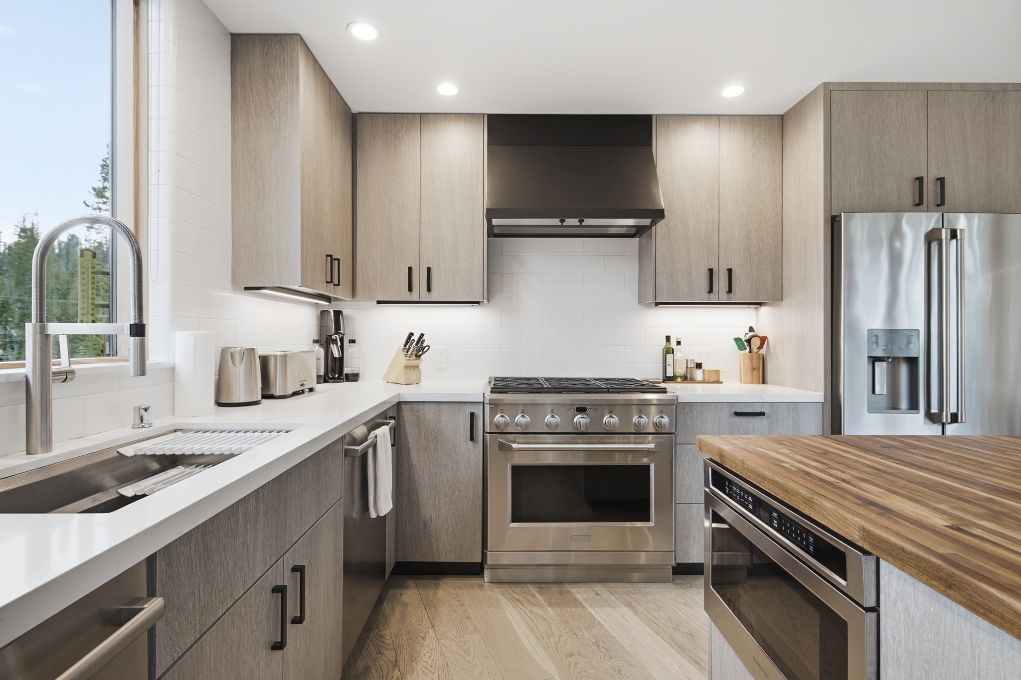 Kitchen with 6-burner gas range, hood, and stainless refrigerator