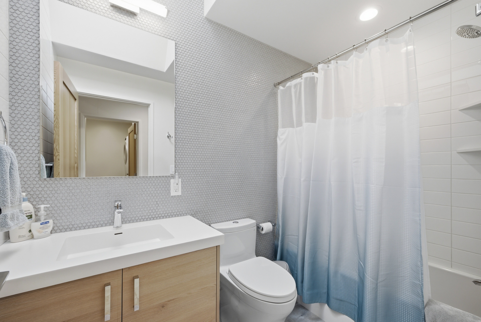 Guest bathroom with penny tile walls, single vanity, and tub/shower combo